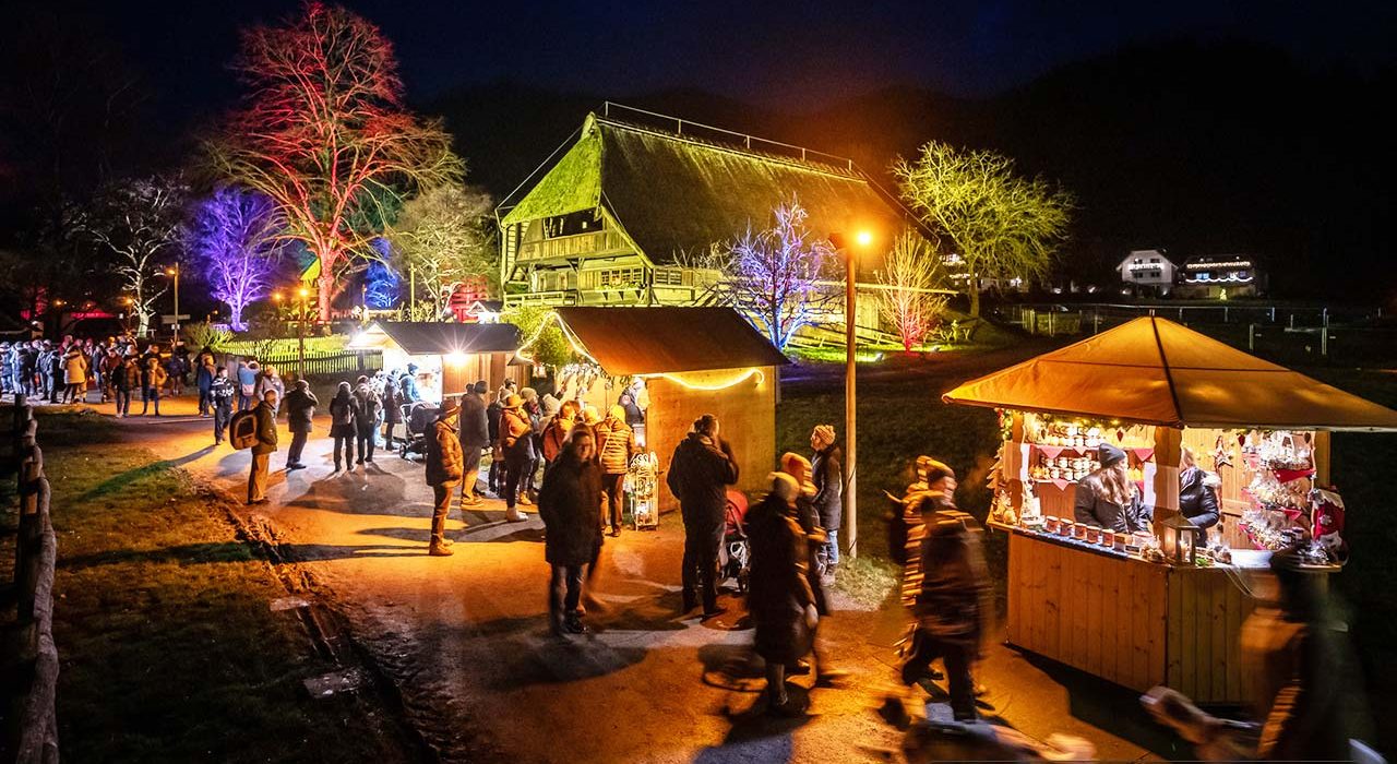 mercadillo de navidad en Vogtsbauernhof Selva Negra Alemania con puestos iluminados y ambiente nocturno